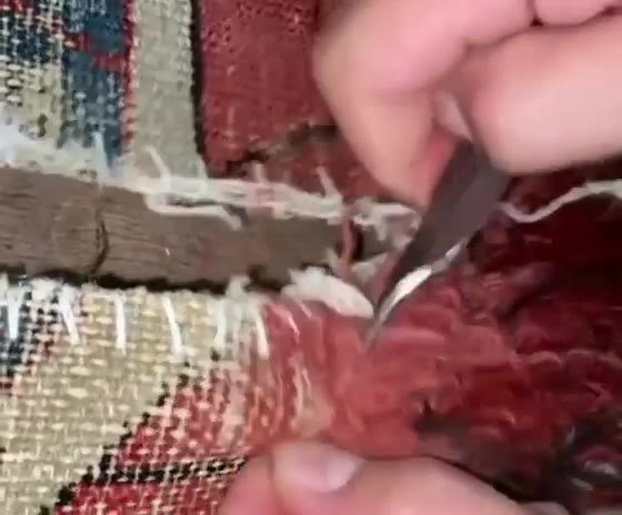 Le crochet passe dans la chaîne et noue la laine, un nœud après l'autre, sur la zone à reprendre.
