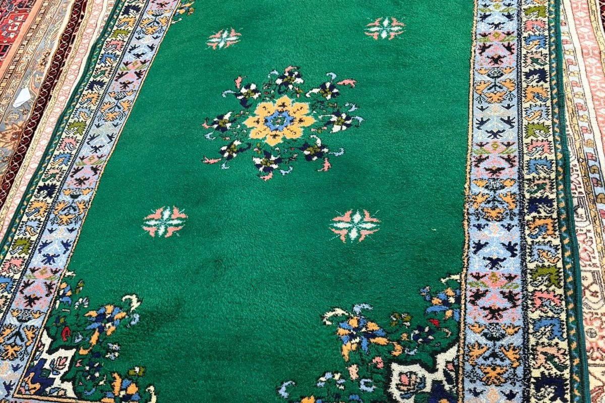 Un tapis chinois à fond vert, velours ciselé autour des motifs.