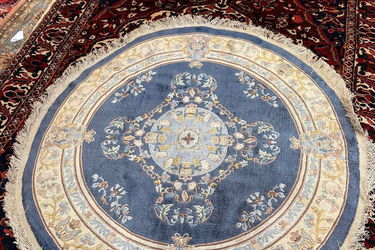 Une pièce ronde en soie, posée sur un tapis de laine.